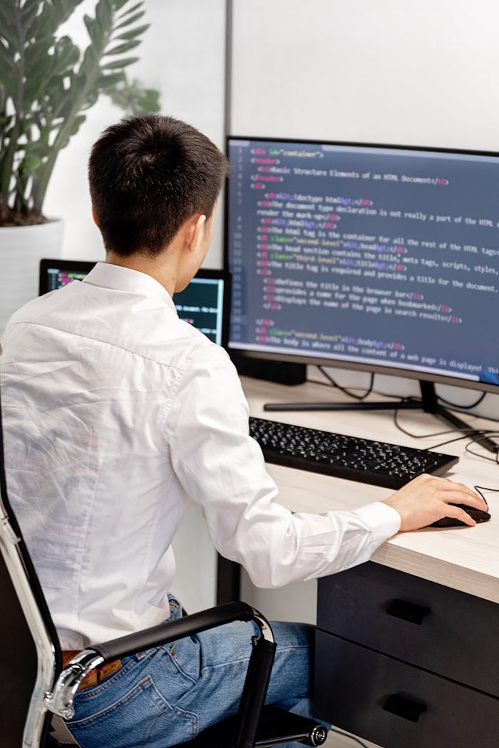 Crafting Captivating Headlines: Your awesome post title goes here Back view of a programmer in a white shirt coding in an office workspace.